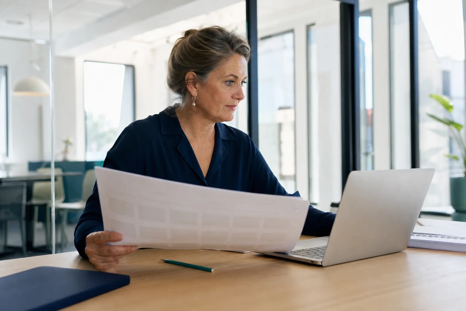 Een medisch adviseur vergelijkt zorgvuldig een dossier met informatie op een laptop